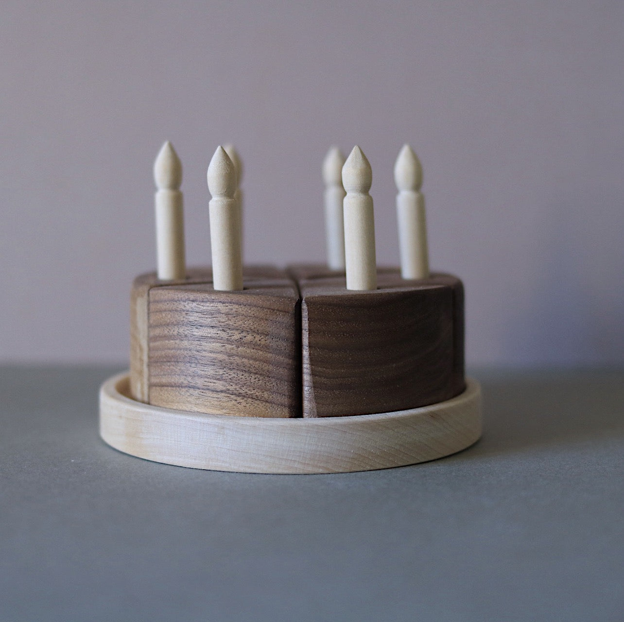 Wooden toy cake with candles on a plain background