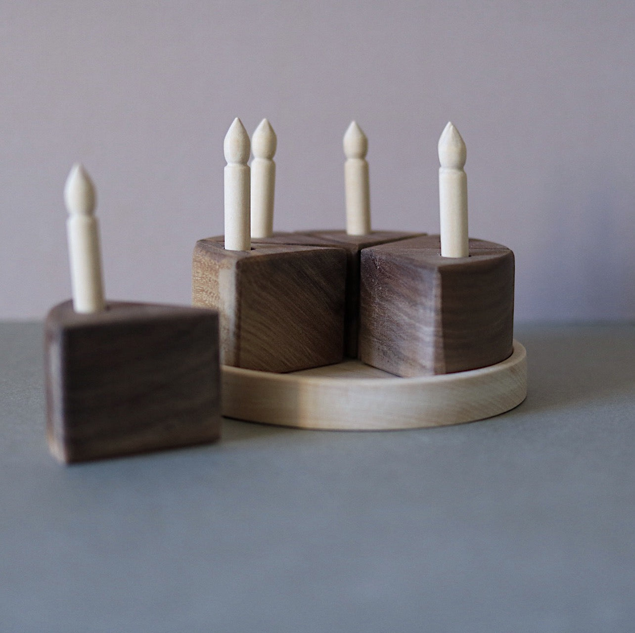 Wooden candle holder with four candles on a gray surface and background