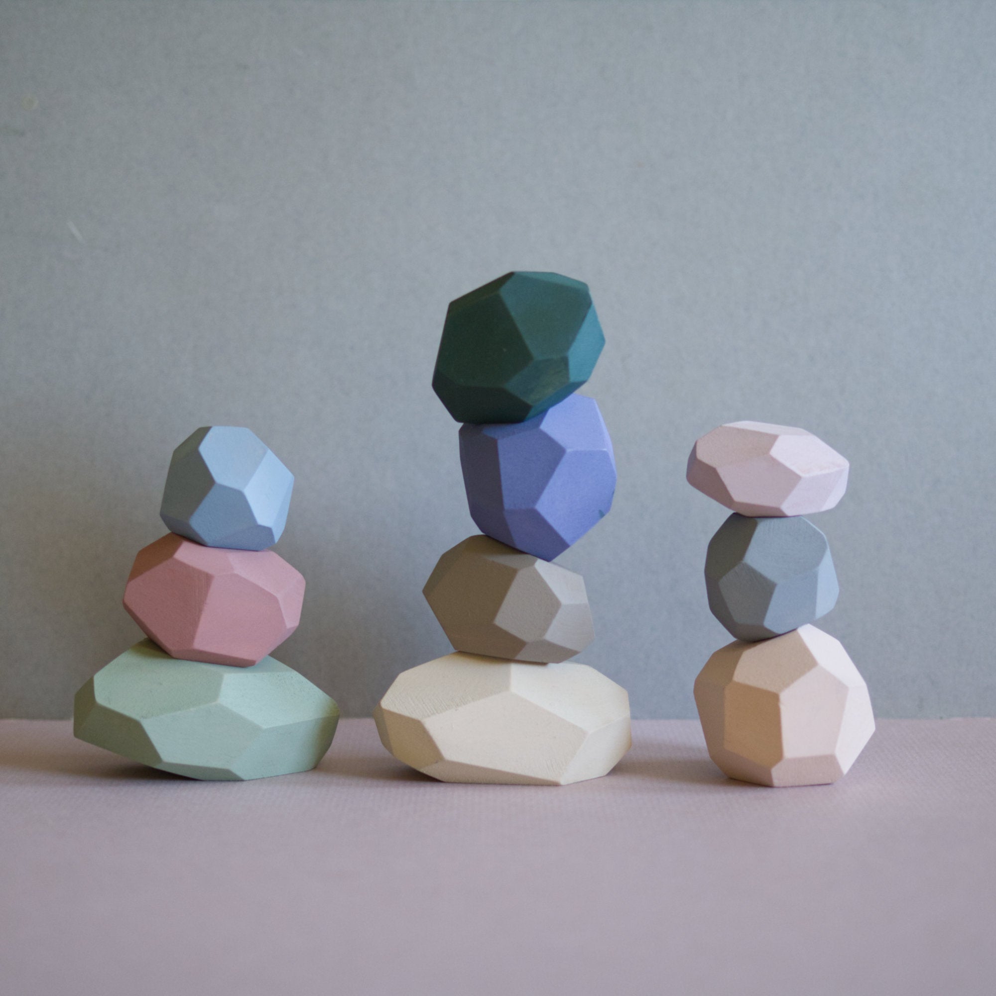 Hand-painted wooden balancing stones in various colors stacked on each other.