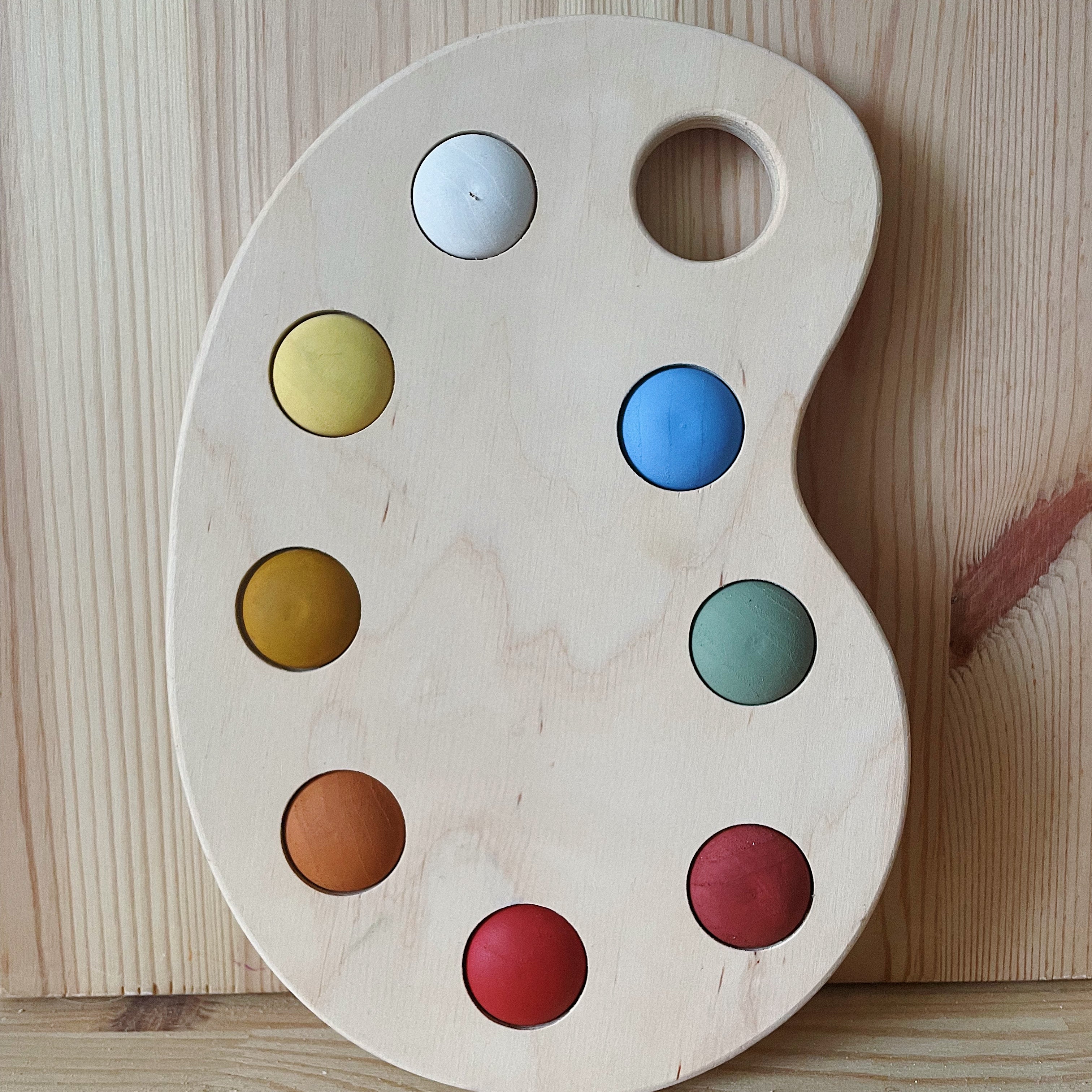A wooden artist's color palette toy with hand-painted colors in various sections