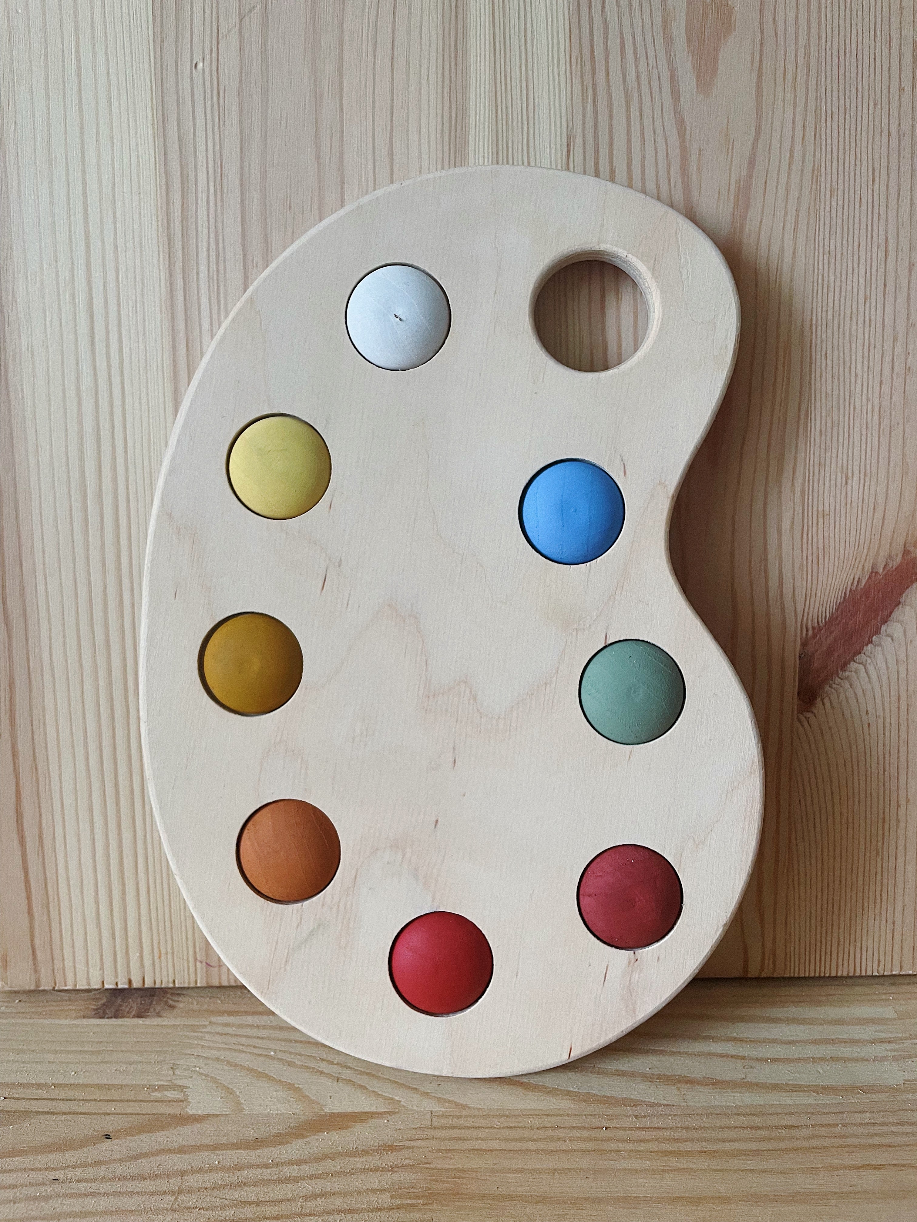 A wooden artist's color palette toy with hand-painted colors in various sections