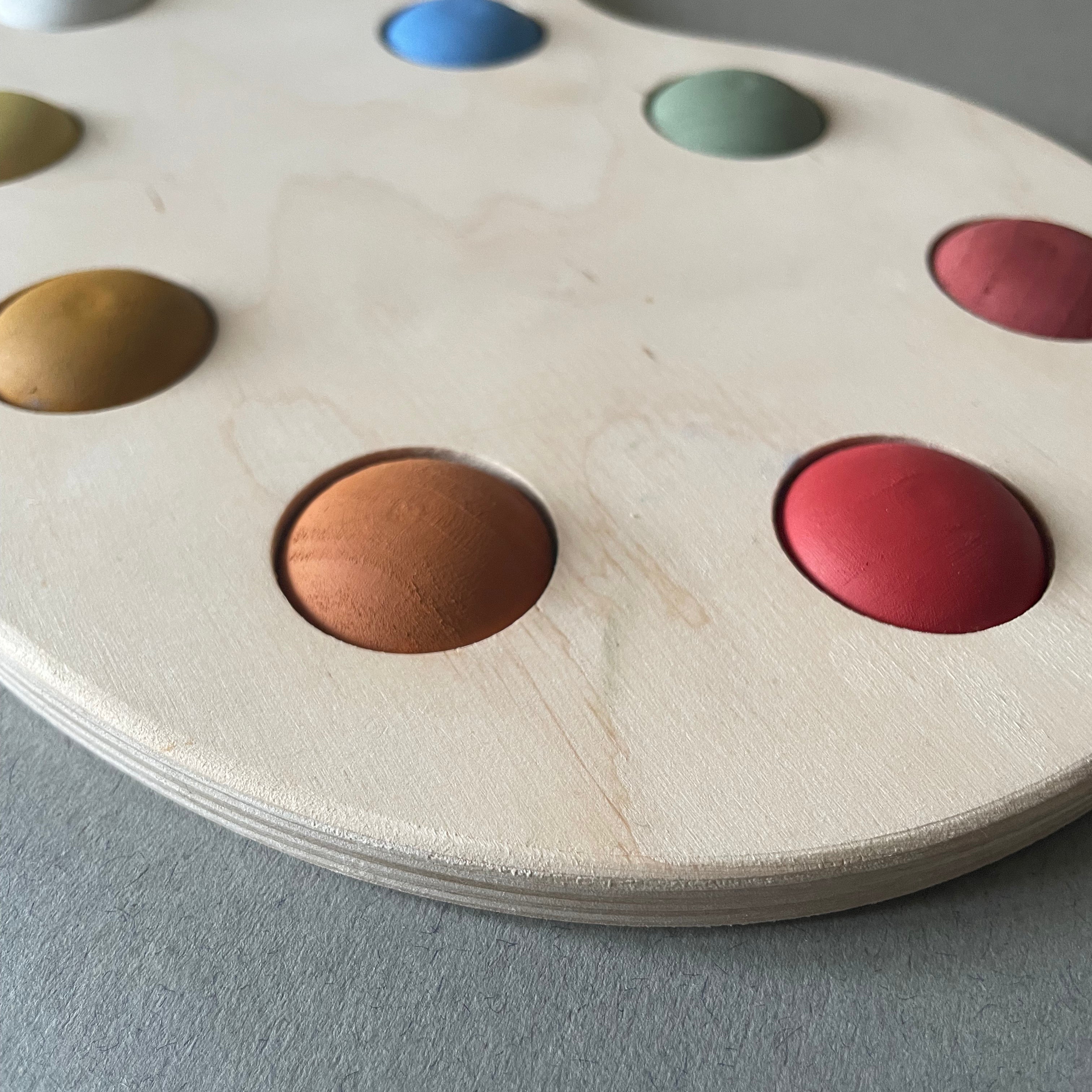 A wooden artist's color palette toy with hand-painted colors in various sections