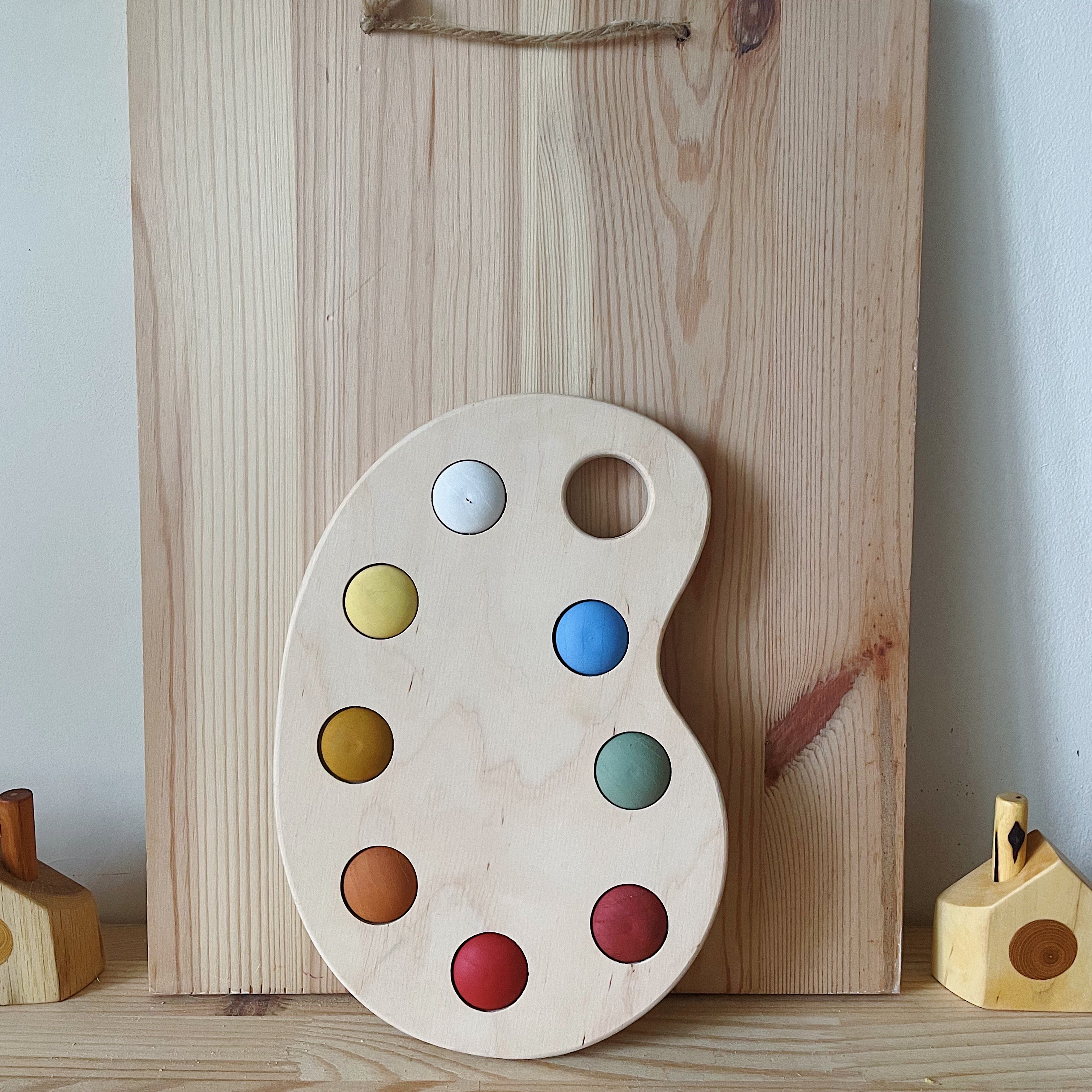 A wooden artist's color palette toy with hand-painted colors in various sections