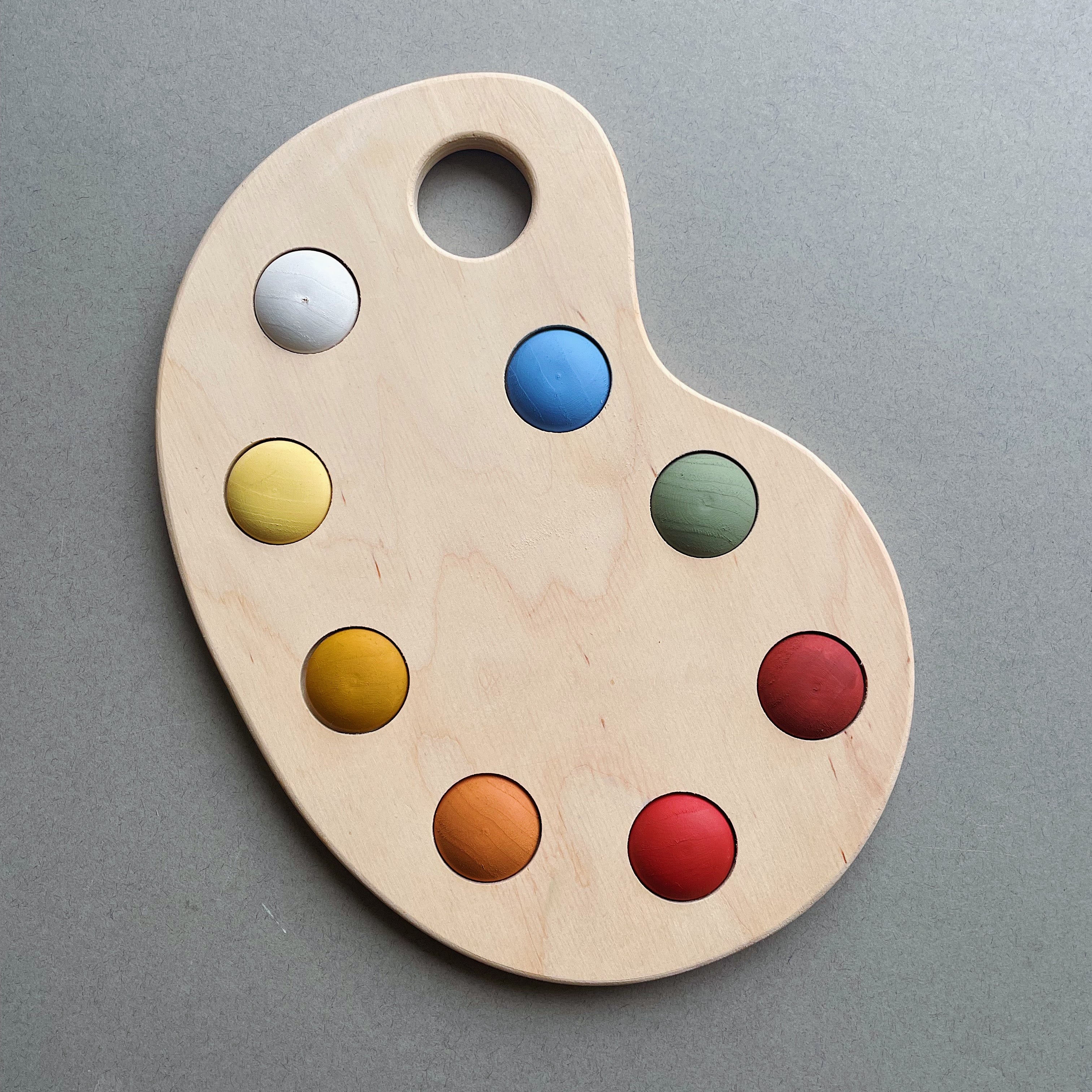 A wooden artist's color palette toy with hand-painted colors in various sections