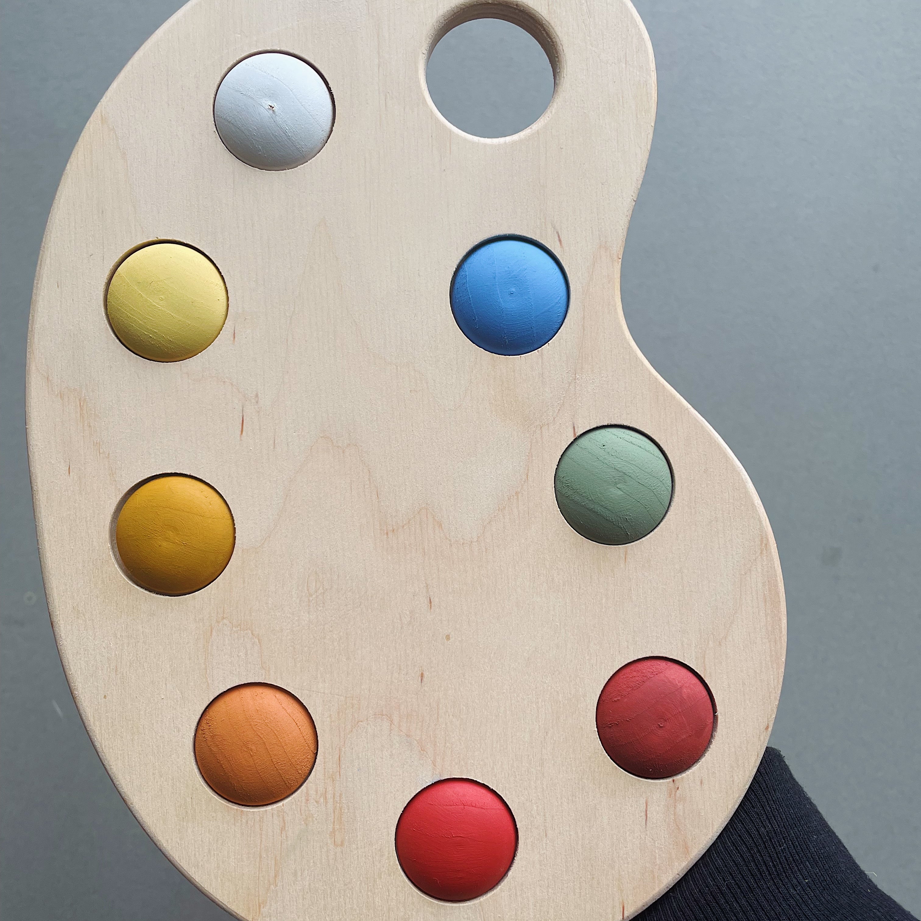 A wooden artist's color palette toy with hand-painted colors in various sections