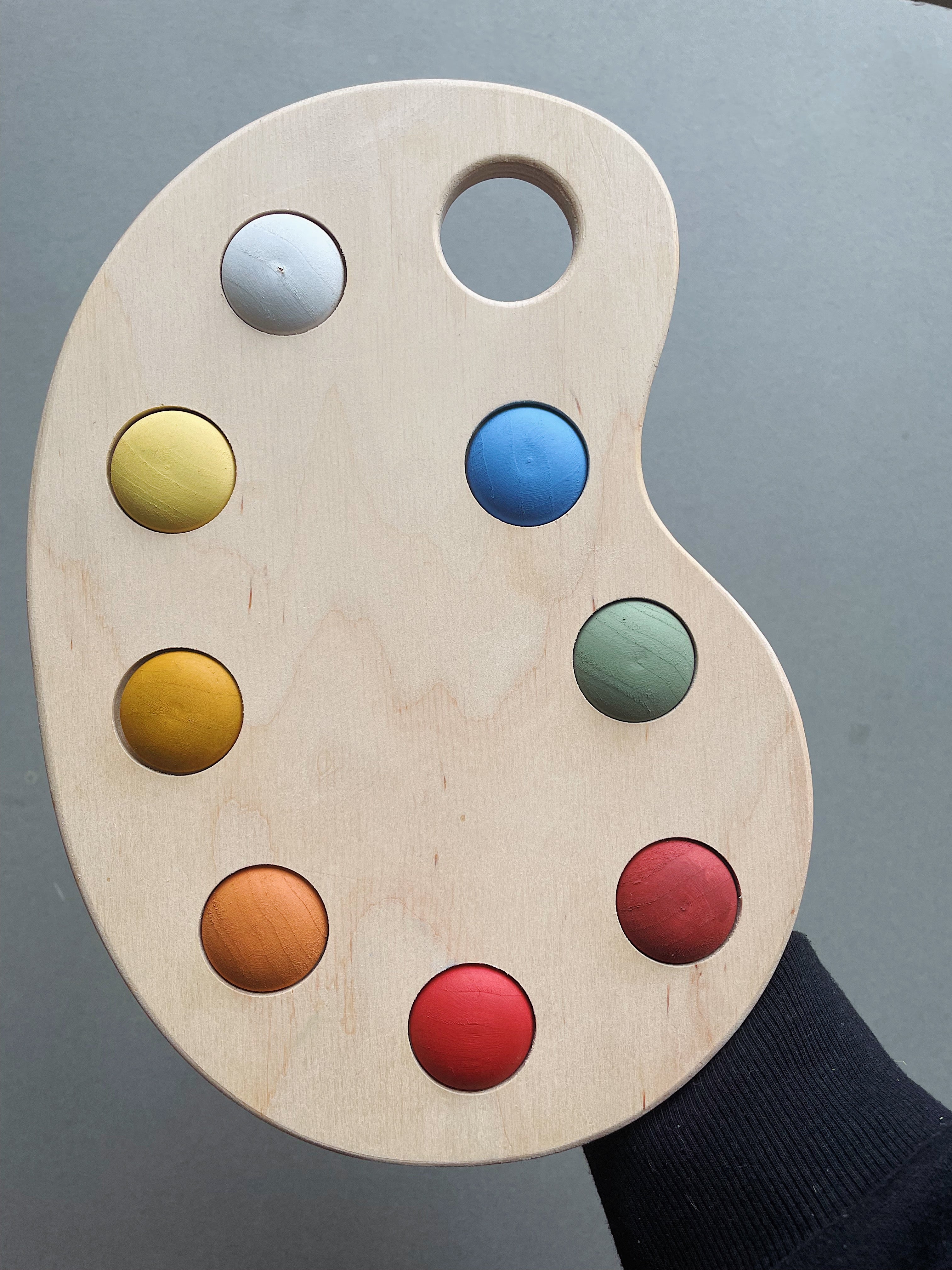 A wooden artist's color palette toy with hand-painted colors in various sections