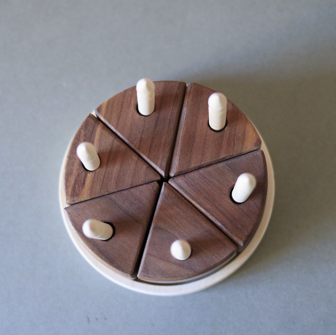 Wooden puzzle with circular base and triangular pieces on a gray background