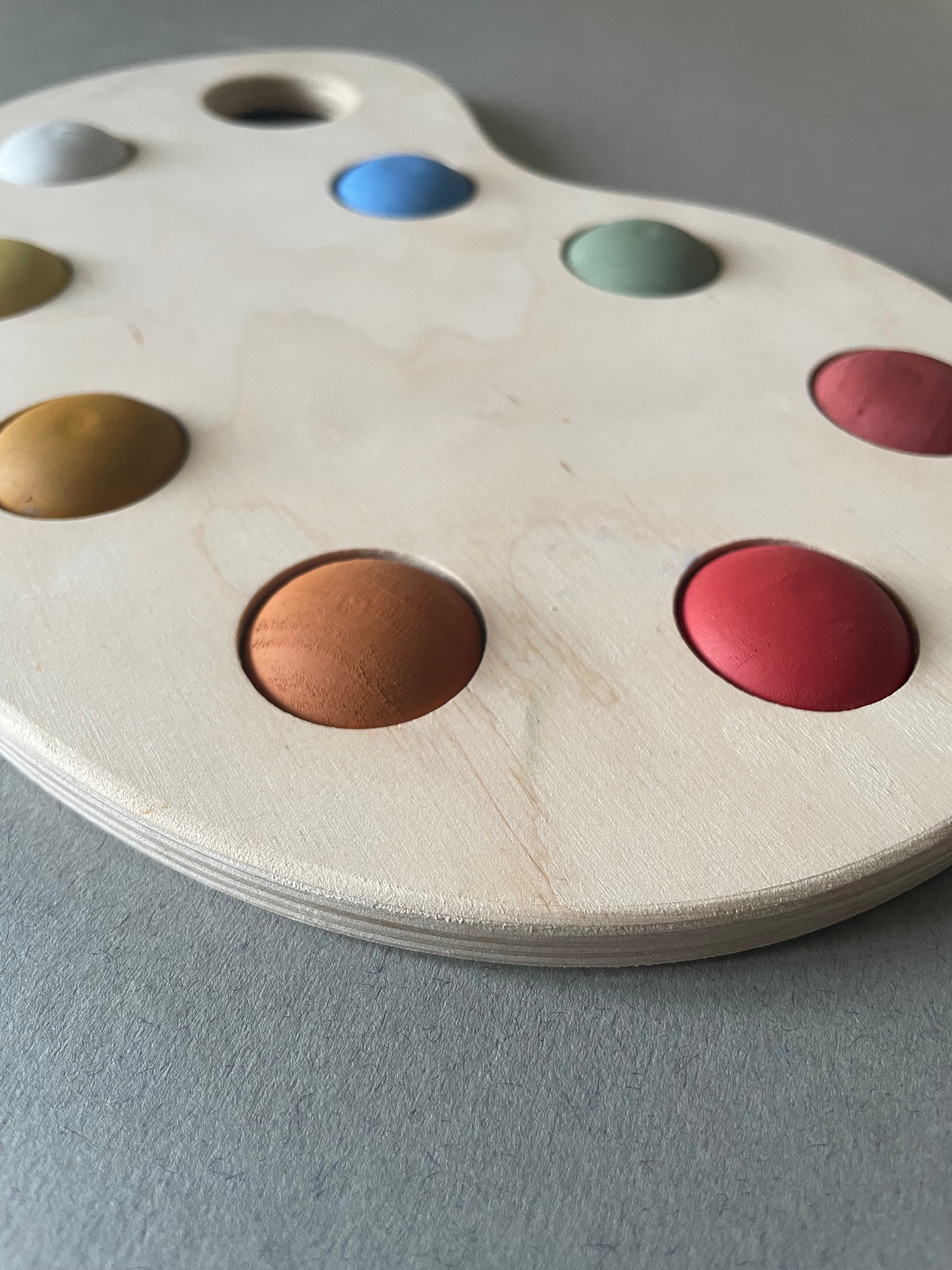 A wooden artist's color palette toy with hand-painted colors in various sections