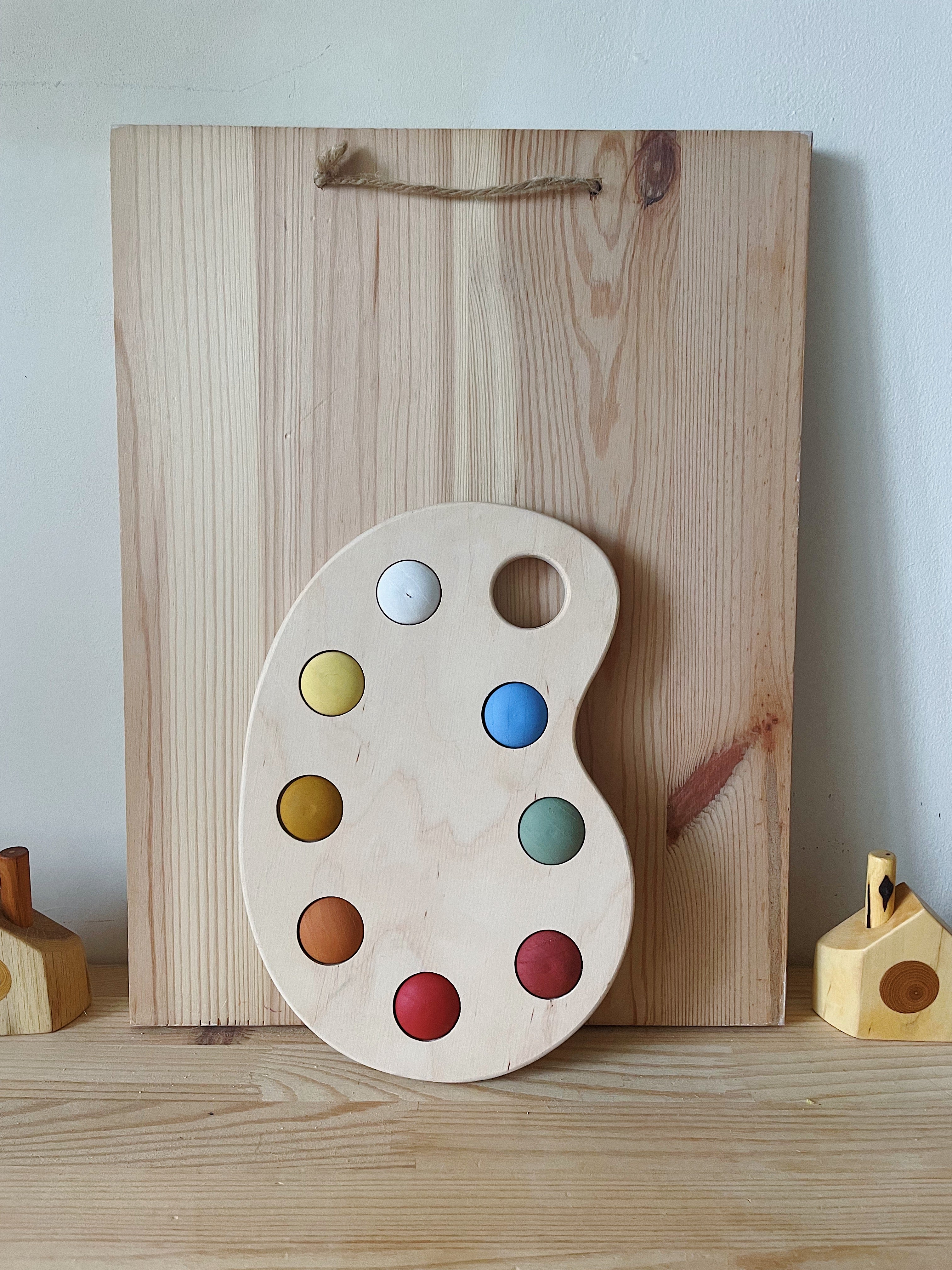 A wooden artist's color palette toy with hand-painted colors in various sections
