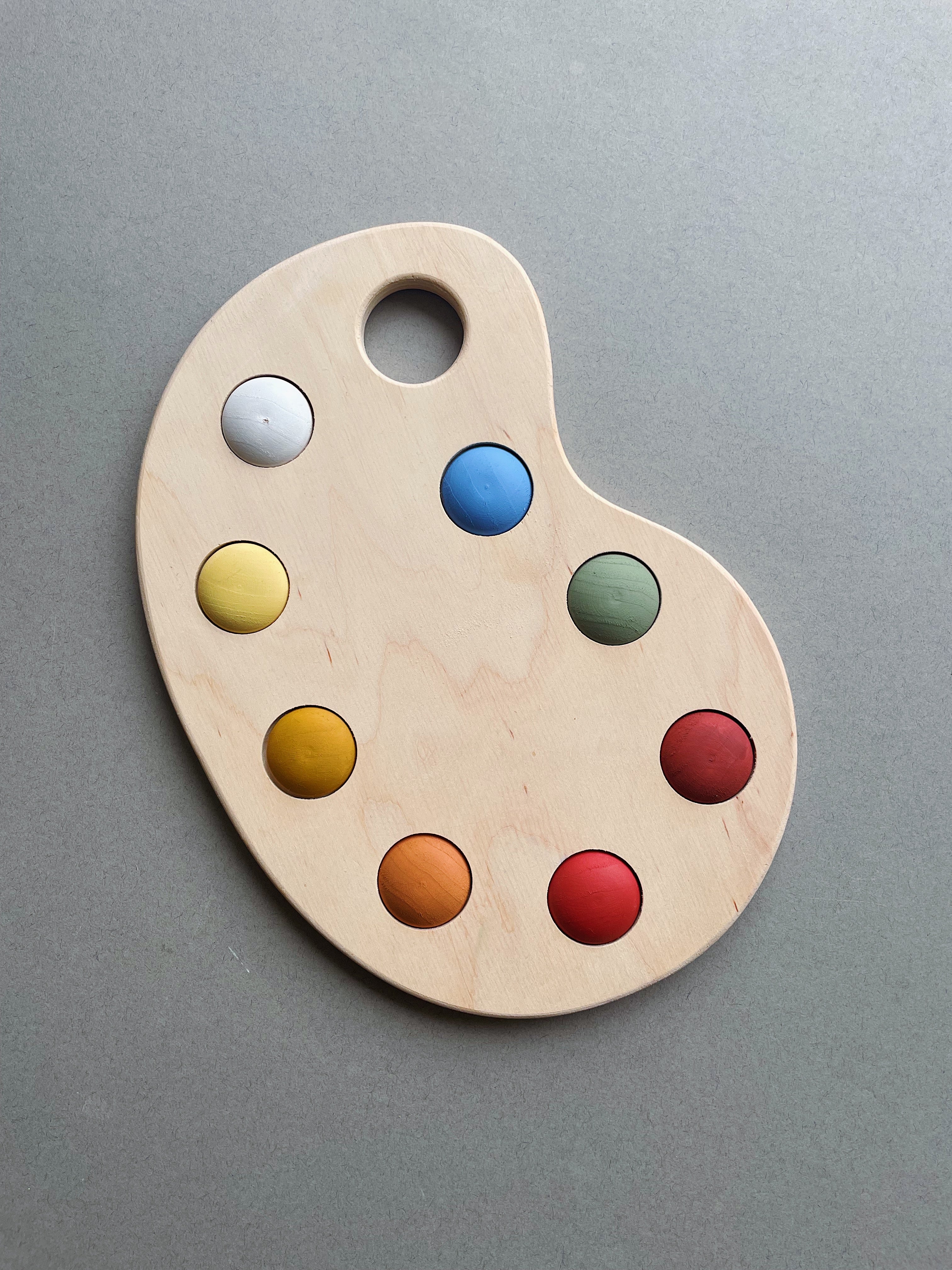 A wooden artist's color palette toy with hand-painted colors in various sections